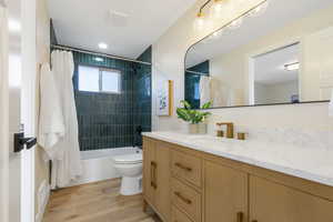 Full bathroom featuring vanity, shower / tub combo with curtain, and light wood finished floors