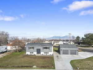 View of front of house with a front lawn, an outbuilding, a garage, and a mountain view