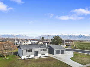 View of front facade with a front lawn, roof with shingles, concrete driveway, and a mountain view
