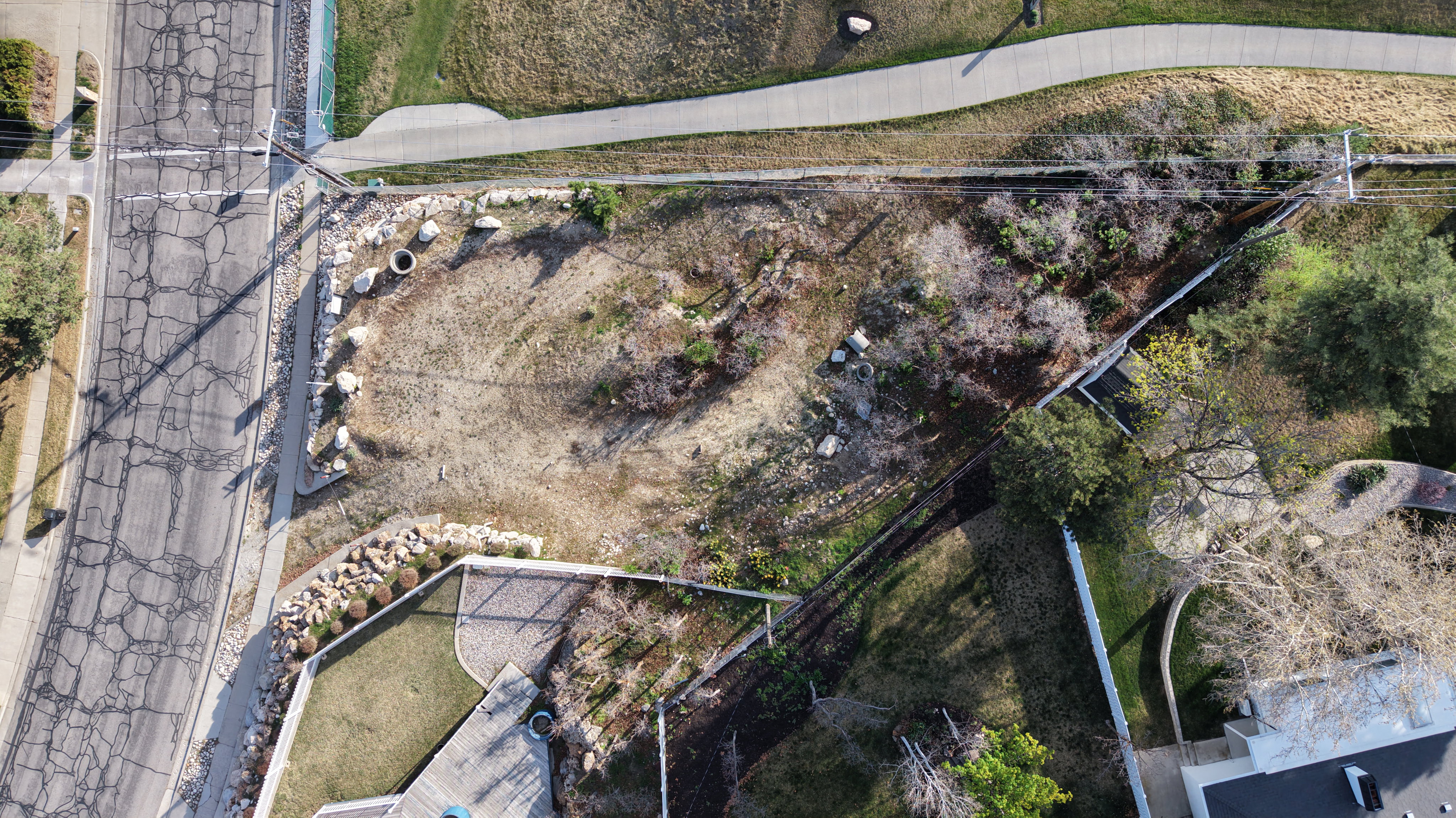 Expansive land parcel with surrounding paved road, sidewalk access, adjacent walking path, and established landscaping
