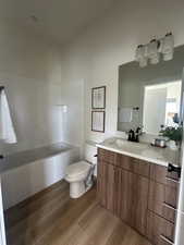 Bathroom with vanity, dark wood-style flooring, and washtub / shower combination