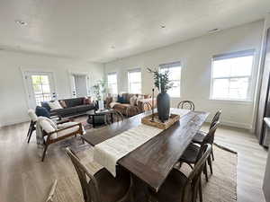 Dining room featuring light wood-style flooring, healthy amount of natural light, and a textured ceiling