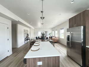 Kitchen with stainless steel fridge with ice dispenser, a breakfast bar, hanging light fixtures, a center island, and open floor plan