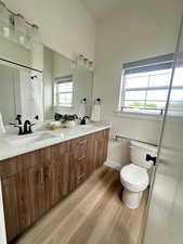 Bathroom featuring double vanity, light wood finished floors, and a shower