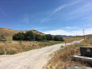 View of dirt / gravel road with a view of rural / pastoral area and a mountain view