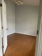 Unfurnished room featuring dark wood-type flooring and a chandelier
