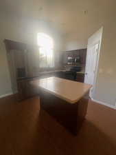 Kitchen with light countertops, a center island, black range with electric stovetop, dark brown cabinets, and stainless steel microwave