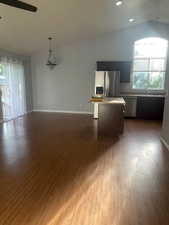 Kitchen featuring vaulted ceiling, light countertops, a ceiling fan, open floor plan, and a center island