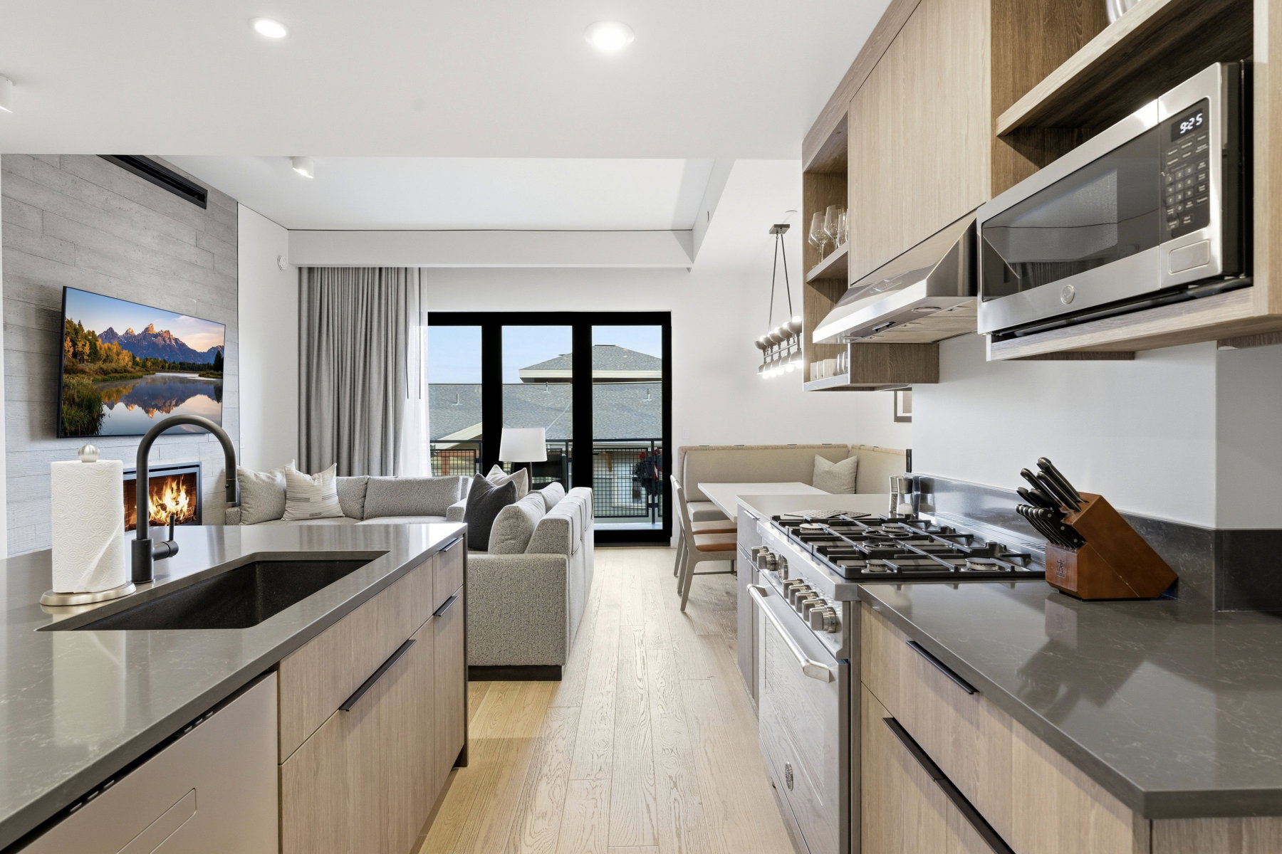 Kitchen with open shelves, stainless steel appliances, light brown cabinetry, and dark stone countertops