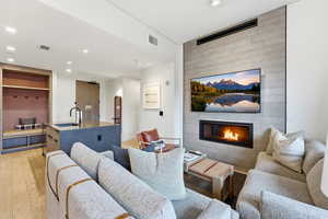 Living room with a fireplace, light wood-type flooring, and recessed lighting