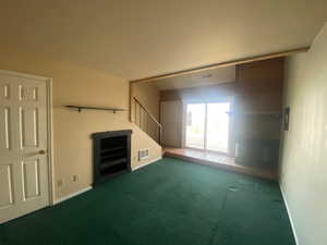 Unfurnished living room featuring carpet floors and baseboards