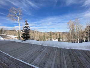 Snow covered deck featuring a wooded view