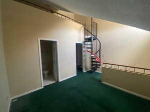 Unfurnished bedroom with carpet floors, a textured ceiling, ensuite bathroom, and a spacious closet