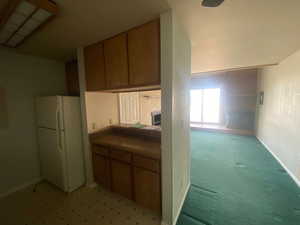 Kitchen with brown cabinets and freestanding refrigerator