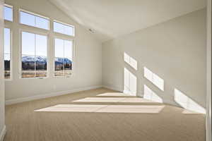 Unfurnished room with carpet flooring, a mountain view, and high vaulted ceiling