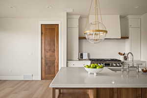 Kitchen featuring light stone countertops, light wood-type flooring, decorative backsplash, a chandelier, and recessed lighting