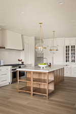 Kitchen featuring white cabinets, custom range hood, range with two ovens, and light wood-style floors