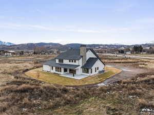 View of front of house with a patio area, a chimney, a mountain view, and a front lawn