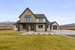 Modern farmhouse style home with board and batten siding, a porch, a mountain view, and a front lawn
