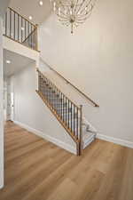Stairway with a high ceiling, wood finished floors, a chandelier, and recessed lighting