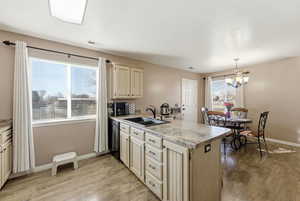 Kitchen featuring light countertops, a peninsula, light wood-style flooring, and light brown cabinets