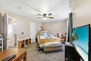 Carpeted bedroom with a textured ceiling, a ceiling fan, and connected bathroom