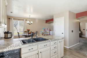 Kitchen featuring light countertops, a peninsula, dishwasher, arched walkways, and a chandelier