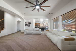 Living area with arched walkways, ceiling fan, stairway, and recessed lighting