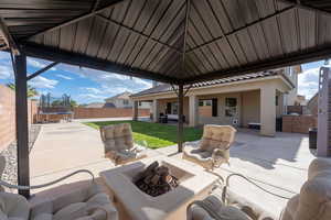Fenced backyard featuring an outdoor living space with a fire pit, a trampoline, a patio area, and a gazebo