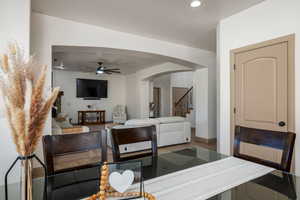 Living room with stairs, a ceiling fan, and arched walkways