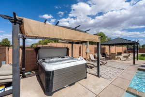 Fenced backyard featuring a hot tub, a patio, an outdoor pool, and a gazebo