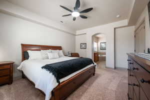 Bedroom with light carpet, arched walkways, and a ceiling fan