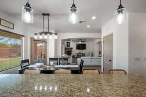 Kitchen featuring decorative light fixtures, a kitchen breakfast bar, a lit fireplace, recessed lighting, and ceiling fan