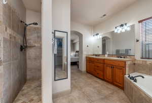 Full bathroom featuring connected bathroom, double vanity, a bath, and light tile patterned flooring