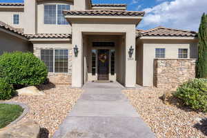 Property entrance with stucco siding, stone siding, and a tiled roof