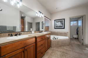 Full bath featuring double vanity, a garden tub, light tile patterned floors, and plenty of natural light
