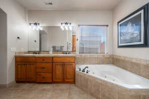 Full bathroom featuring double vanity, a whirlpool tub, and light tile patterned floors