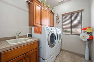 Laundry area featuring cabinet space, separate washer and dryer, and light tile patterned floors