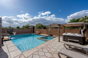 View of swimming pool featuring a fenced backyard, a patio, a water slide, and a pool with connected hot tub