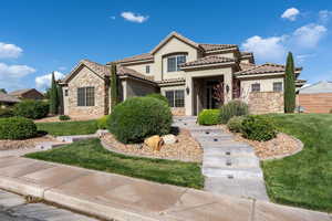 Mediterranean / spanish-style home with stone siding, stucco siding, a front yard, and a tile roof