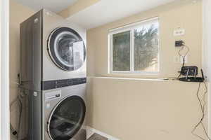 Laundry room featuring stacked washer / dryer and baseboards