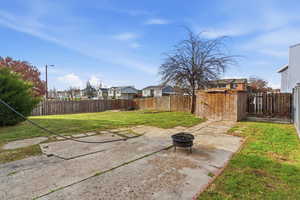 Fenced backyard with an outdoor fire pit, a patio, and a residential view
