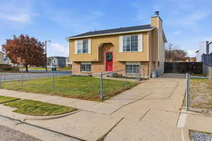 Split foyer home with brick siding, a chimney, a fenced front yard, and concrete driveway