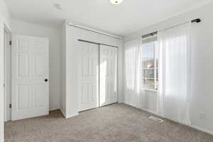 Bedroom with light colored carpet and a closet