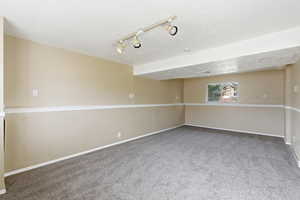 Below grade area with track lighting, carpet, and a textured ceiling