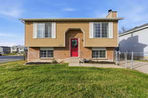 Raised ranch featuring brick siding, a gate, and a chimney