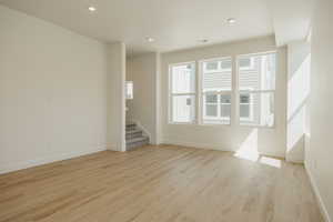 Unfurnished room featuring stairs, light wood-style flooring, and recessed lighting