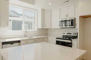 Kitchen featuring appliances with stainless steel finishes, white cabinetry, and a center island