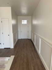 Doorway to outside with wood finished floors, a decorative wall, and wainscoting