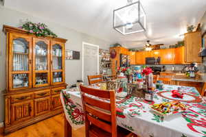 Dining space with light wood-style flooring, ceiling fan, and a chandelier